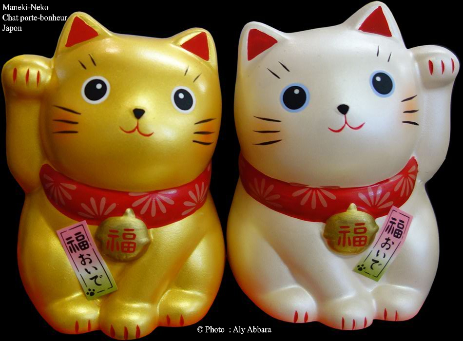 Deux Maneki-Neko, le premier est doré, à patte de devant droite levée (version masculine) et le deuxième est blanc, à patte de devant gauche levée (version féminine)